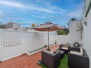 a patio with an umbrella and chairs and a fence at Private Chill-out Terrace Bungalow - Pool in San Bartolomé de Tirajana