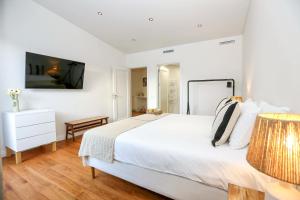 a white bedroom with a large bed and a television at Green Essence Duplex in Faro by Misha's Place in Faro