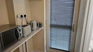 a kitchen with a counter with a microwave and a television at Convenient En-suite Double in Oxford