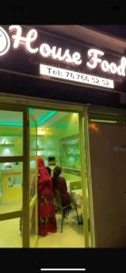 Una mujer sentada en una silla afuera de una tienda en House & Food, en Thiès