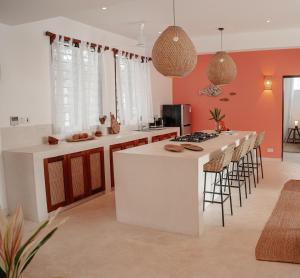 a kitchen with orange walls and a white island with bar stools at Eden Escapes - Diani Beach, Kenya in Diani Beach