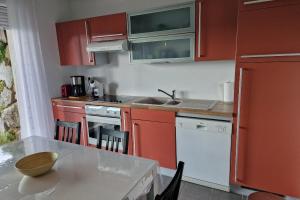 a kitchen with red cabinets and a table with a bowl on it at Appartement avec vue sur le lac de Gérardmer, proche des pistes de ski in Gérardmer +3 photos