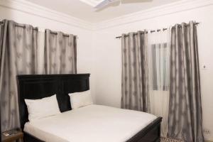 a bed in a bedroom with gray curtains at EJ Apartments in Madina Dabo Kunda