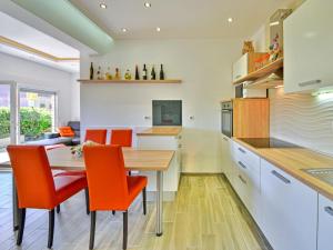 kuchnia z drewnianym stołem i pomarańczowymi krzesłami w obiekcie Holiday Home Koalas Nest Home & Apartments by Interhome w mieście Matulji