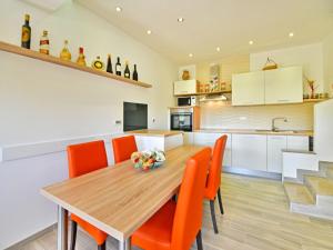 kuchnia i jadalnia z drewnianym stołem i pomarańczowymi krzesłami w obiekcie Holiday Home Koalas Nest Home & Apartments by Interhome w mieście Matulji