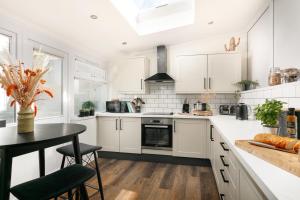 a kitchen with white cabinets and a black table at NEW LUXURY for 2024 - Central Plymouth House - Sleeps 10 - Access to Plymouth Town - Close to The Barbican - Pets welcome - Parking Available - By Luxe Living by Sophia in Plymouth