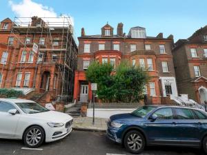 two cars parked in a parking lot in front of a building at Pass the Keys Elegant flat in trendy Hampstead in London