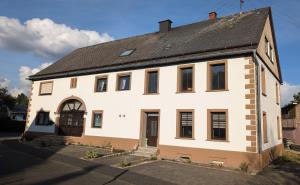 an old white house with a black roof at Ferienwohnung am Nationalpark Hunsrück Hochwald in Brücken