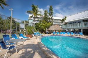 a swimming pool with chairs and a table and a building at Oceanfront Oasis in Key West