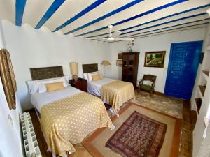 1 Schlafzimmer mit 2 Betten und einer blauen und weißen Decke in der Unterkunft Finca La Alcolehuela en Parque Natural de Despeñaperros in Santa Elena