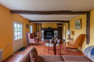 a living room with a couch and a table at Fleurs De Mai Cottage Heated Pool Playgrounds View in Ablon