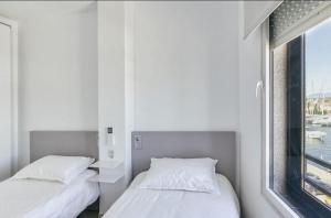 two beds in a room with a window at Apartamento con vistas a mar y canal. Empuriabrava in Empuriabrava