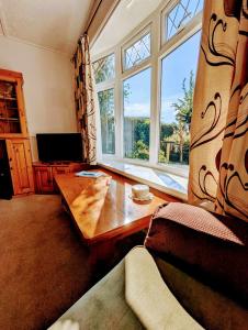 Una sala de estar con una mesa y una gran ventana. en 2-Bed Bungalow Retreat, Welcombe, en Welcombe
