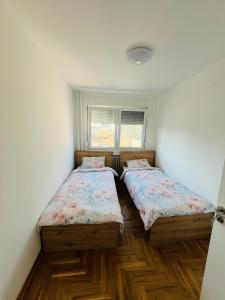 two beds in a room with wooden floors at Apartment Ninana in Belgrade