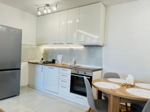 a kitchen with white cabinets and a table with chairs at Apartment Ninana in Belgrade