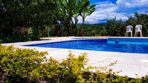 a swimming pool with two chairs in a yard at La Martina Palestina in Palestina