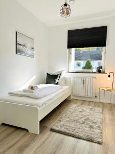a white bedroom with a bed and a window at Großzügige Wohnung - 6 Personen-3 Schlafzimmer- Parkplatz- Waschmaschine-2 Balkone in Wolfsburg