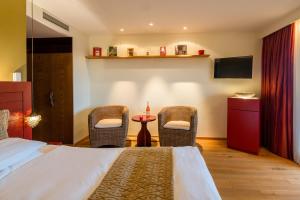 a bedroom with a bed and two chairs and a table at Hotel Heiligenstein in Baden-Baden