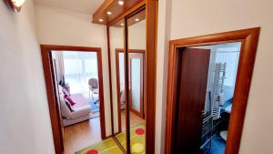 a hallway with two mirrors and a living room at Jokai sor II Apartman in Hajdúszoboszló