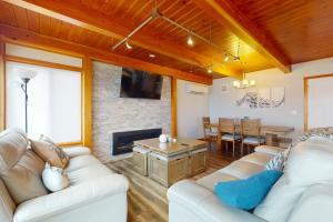 a living room with white couches and a fireplace at Whalehouse in Tyee Beach