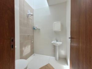 a white bathroom with a toilet and a sink at Casa de praia com wi-fi in Barra Velha