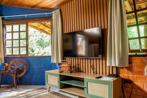 a living room with a tv on a wall at Casa do Tecelão - Refúgio, jardim e tranquilidade in Curitiba