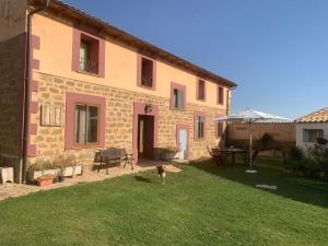 a dog standing in the yard of a house at Hotel Rural El Cielo Entejado in Tejado