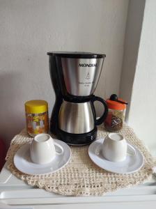 a coffee maker sitting on top of a table with saucers at Hospedagem casa da Lu in Paraty
