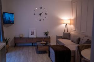 a living room with a couch and a clock on the wall at Zena Apartment in Ocna-Mureşului