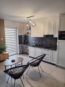 kuchnia z białymi szafkami, stołem i krzesłami w obiekcie Apartament Górska Szarotka w Nowym Targu