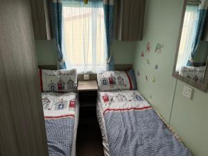 two beds in a small room with a window at Millie’s caravan in Abergele