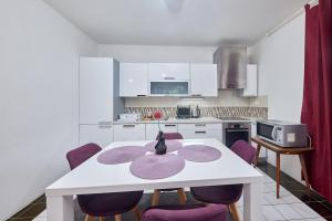 a kitchen with a white table and purple chairs at Relax apartment in Bratislava