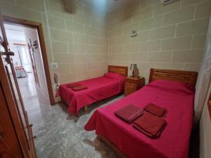 - 2 lits dans une chambre avec des draps rouges dans l'établissement Attard Seafront Apartment 3 in Marsalforn, à Żebbuġ