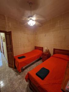 泽布季Attard Seafront Apartment 7 in Marsalforn的一间卧室配有两张带橙色床单的床
