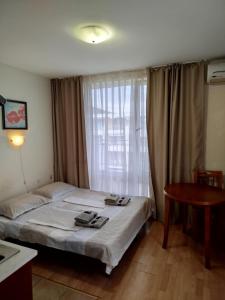 a bedroom with a bed and a table and a window at Aria private apartments in Fort Noks Grand Resort - Saint Vlas in Elenite