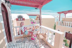 a woman sitting at a table on the balcony of a house at Villa Dima in Perissa +41 photos
