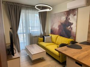 a living room with a yellow couch and a painting at Luxury flat in Pleven in Pleven