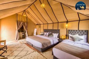 a bedroom with two beds in a tent at Anir Luxury Camp - Gites et Tentes de Luxe in Merzouga