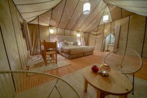 a bedroom with a bed and a table in a tent at Anir Luxury Camp - Gites et Tentes de Luxe in Merzouga