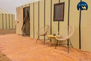 two chairs and a table in front of a building at Anir Luxury Camp - Gites et Tentes de Luxe in Merzouga