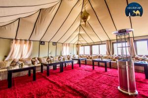 a large tent with couches and a red carpet at Anir Luxury Camp - Gites et Tentes de Luxe in Merzouga