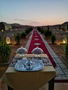 a table in the middle of a desert with a red carpet at Anir Luxury Camp - Gites et Tentes de Luxe in Merzouga
