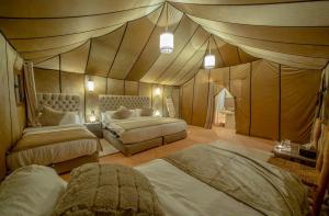 a bedroom with two beds in a tent style room at Anir Luxury Camp - Gites et Tentes de Luxe in Merzouga