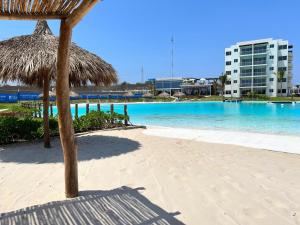 a beach with a straw umbrella and a swimming pool at Blue Mazatlán in Mazatlán