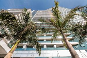 Un edificio alto con palmeras delante. en Apartamento 1 Quarto Lindíssimo, Garagem - SEV2402, en Curitiba