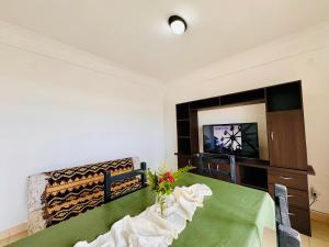 a dining room with a green table and a television at Departamento A Mar in Mar del Plata