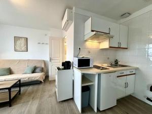 een keuken en een woonkamer met een bank bij L'Océane, studio spacieux avec place de parking, Proche plage in La Palud