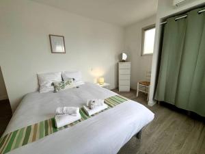 een slaapkamer met een groot wit bed met handdoeken erop bij L'Océane, studio spacieux avec place de parking, Proche plage in La Palud