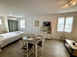 een slaapkamer met een bed en een tafel met stoelen bij L'Océane, studio spacieux avec place de parking, Proche plage in La Palud