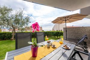 een eettafel met een parasol op een patio bij Apartment Elegance in Krk